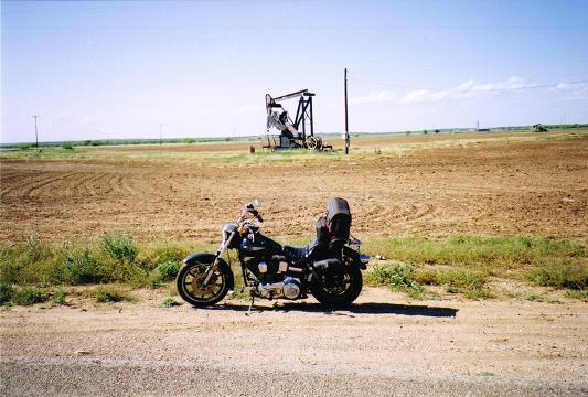 [The Harley parked next to one of the first oil pumps that I saw on this trip.]